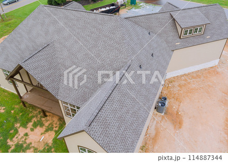 Rubber asphalt roof shingles are being used to cover construction roof of new house Rubber asphalt roof shingles are being used to cover construction roof of new house 114887344