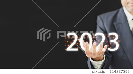 A man is holding up a sign that says "2023" in glowing letters A man is holding up a sign that says "2023" in glowing letters 114887595