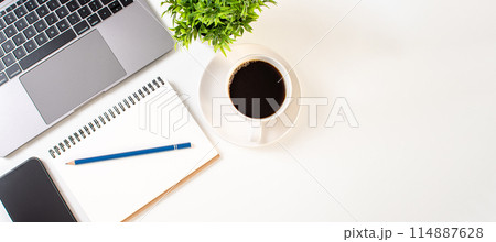 A laptop, a notebook, a pen, and a cup of coffee sit on a table A laptop, a notebook, a pen, and a cup of coffee sit on a table 114887628