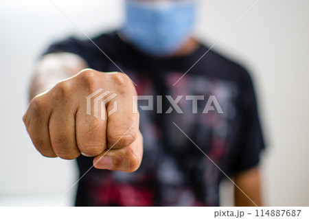 A man wearing a black shirt and a blue mask is punching the air 114887687