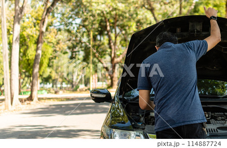 A man is standing next to a car with the hood up A man is standing next to a car with the hood up 114887724