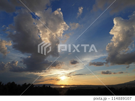 猪苗代湖対岸に沈むオレンジ色の夕日。太陽が上空の雲を白く輝かせ、湖面も輝く。青空に印象的で綺麗だ。 猪苗代湖対岸に沈むオレンジ色の夕日。太陽が上空の雲を白く輝かせ、湖面も輝く。青空に印象的で綺麗だ。 114889107