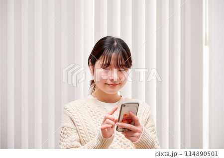 家でスマホを操作する女性 114890501