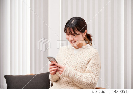 家でスマホを操作する女性 114890513