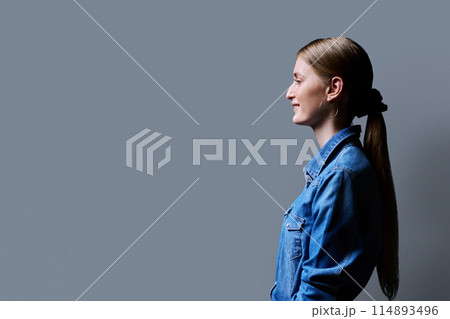 Profile view, young smiling female looking forward on gray studio background Profile view, young smiling female looking forward on gray studio background 114893496