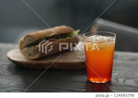 orange lemonade with baguette sandwich on background on black wood table orange lemonade with baguette sandwich on background on black wood table 114893790
