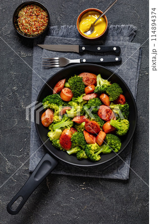 fried juicy sausage and crispy broccoli in skillet 114894374