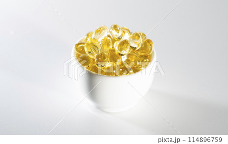 Transparent yellow vitamins on a light background. Vitamin D, omega 3, omega 6, Food supplement oil filled fish oil, vitamin A, vitamin E, flaxseed oil. 114896759