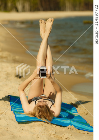 Woman in bikini sunbathing and relaxing on beach 114897722