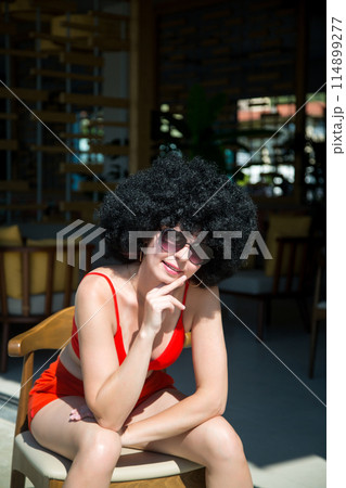A saleswoman of a street store sunbathes on a hot summer day near the entrance 114899277