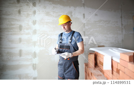 Male builder in yellow hard hat holds Male builder in yellow hard hat holds 114899531