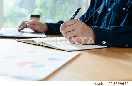 資料を見る男性の手元 114899679