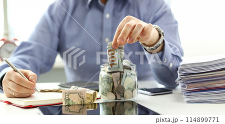 Male hand depositing some extra money in future needs 114899771