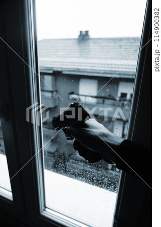 Gunman holding pistole in window Gunman holding pistole in window 114900382