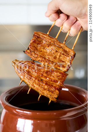 鰻の蒲焼をタレに漬ける 鰻の蒲焼をタレに漬ける 114900949