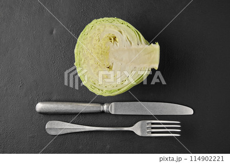 White cabbage in a cut, fork and knife on a black stone tabletop 114902221
