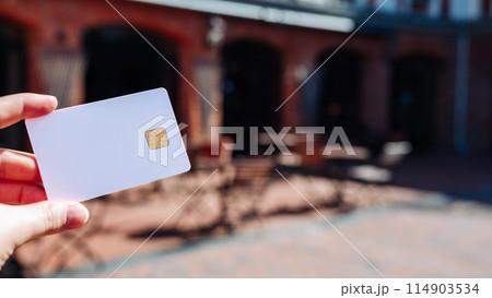 A person is holding a white credit card with a gold chip A person is holding a white credit card with a gold chip 114903534