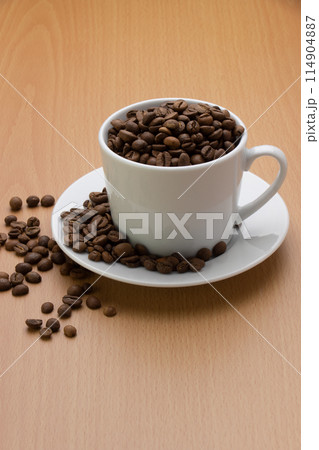 コーヒーカップから溢れたコーヒー豆を縦位置で中段に配置 コーヒーカップから溢れたコーヒー豆を縦位置で中段に配置 114904887