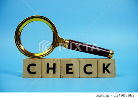 Check with wooden blocks alphabet letters and Magnifying glass on blue background 114905968