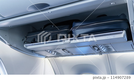 Overhead bin of a plane neatly packed with luggage, demonstrating efficient air travel storage. 114907289