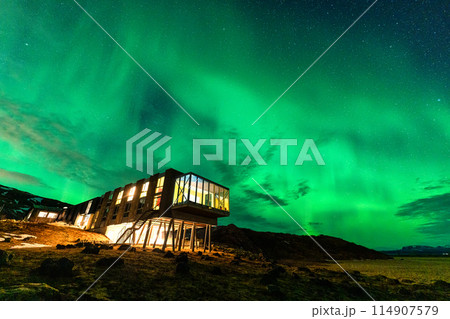 Aurora borealis, Northern lights glowing over luxury hotel on volcanic wilderness in winter at Iceland 114907579