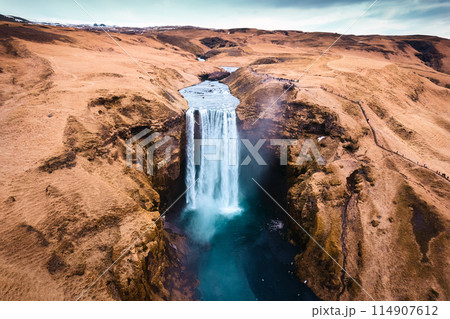 Aerial drone view of Majestic powerful Skogafoss waterfall flowing from cliff among brown mountain in autumn at Southern of Iceland 114907612
