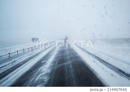 Car driving on snow covered highway road and blizzard with windy in countryside at Iceland 114907648