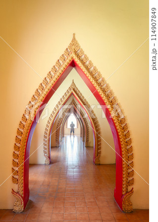Traditional golden arch door with male tourist in corridor at Wat Tham Sua, Kanchanaburi Traditional golden arch door with male tourist in corridor at Wat Tham Sua, Kanchanaburi 114907849
