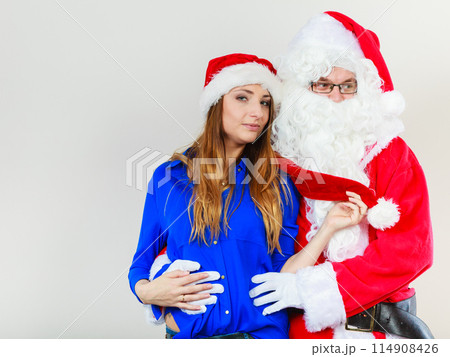 Santa Claus hugging woman with christmassy hat Santa Claus hugging woman with christmassy hat 114908426