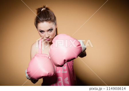 Female boxer wearing big fun pink gloves playing sports Female boxer wearing big fun pink gloves playing sports 114908614