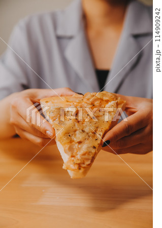Cropped image of woman holding pizza slice at restaurant Cropped image of woman holding pizza slice at restaurant 114909242