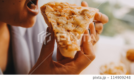 Cropped image of woman holding pizza slice at restaurant 114909248