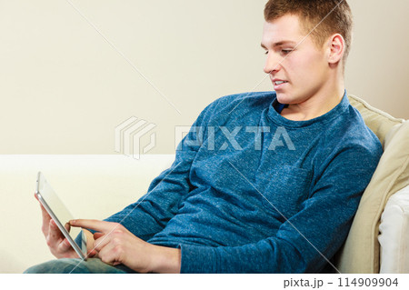 Young man with digital tablet sitting on couch 114909904