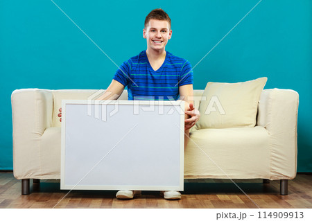 man on sofa holding blank presentation board man on sofa holding blank presentation board 114909913