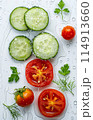 slices of cucumbers and tomatoes with greenery in drops of water, white background 114913660