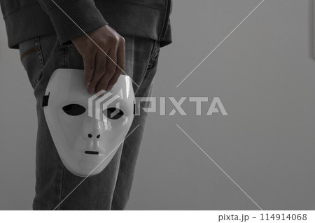 白い仮面を外して持つ男性 114914068