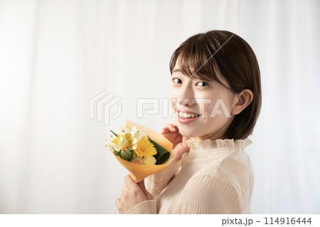 ミニブーケを持って微笑む女性 114916444