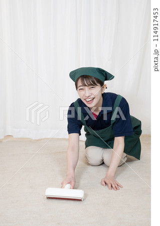 カーペットクリーナーで掃除をするハウスクリーニングの女性作業員 114917453