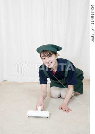 カーペットクリーナーで掃除をするハウスクリーニングの女性作業員 114917454