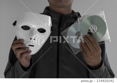 白い仮面とCDとUSBメモリを持つ男性。情報漏洩イメージ 白い仮面とCDとUSBメモリを持つ男性。情報漏洩イメージ 114920242
