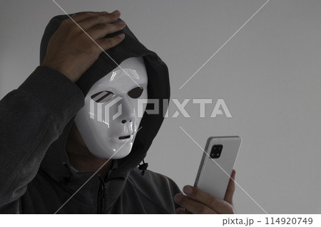 白い仮面をつけスマートフォンを持つ男性。頭を抱える 114920749