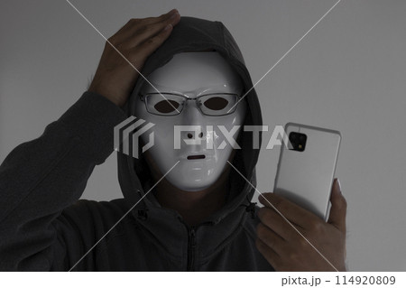 白い仮面と眼鏡をつけスマートフォンを持つ男性。頭を抱える 白い仮面と眼鏡をつけスマートフォンを持つ男性。頭を抱える 114920809