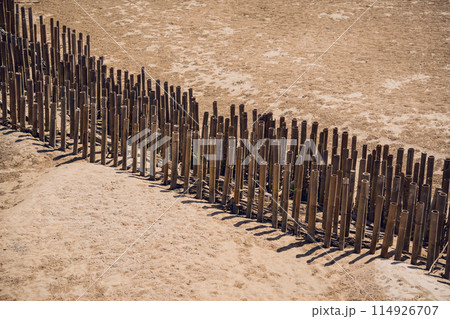 A wooden fence stands in the center of a dusty field A wooden fence stands in the center of a dusty field 114926707