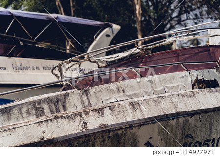 Old and rusty motor boats on a landfill surrounded by tropical forest Old and rusty motor boats on a landfill surrounded by tropical forest 114927971