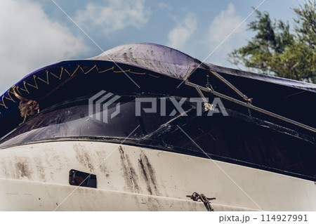 Old and rusty motor boats on a landfill surrounded by tropical forest Old and rusty motor boats on a landfill surrounded by tropical forest 114927991