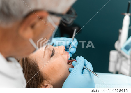 In the dental office, the doctor uses modern technologies and equipment for treatment. The patient in the chair feels confident in the effectiveness and advanced methods of dental treatment. 114928413