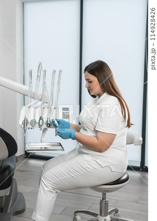 Modern equipment is visible in the background, which indicates the high professional level of the doctor and her willingness to provide the best dental care. With stylish design and expressions of Modern equipment is visible in the background, which indicates the high professional level of the doctor and her willingness to provide the best dental care. With stylish design and expressions of 114928426