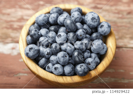 Blueberry berries are in a wooden plate on wooden background. Healthy food and healthy lifestyle. 114929422