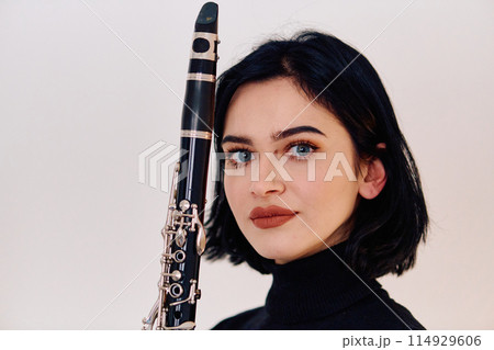 Graceful Brunette Musician Posing with Clarinet on White Background 114929606