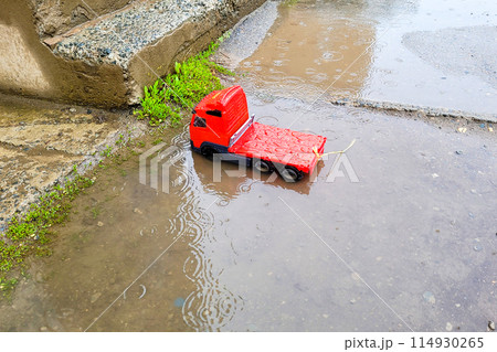 A children's toy car was left near the entrance to the house. Car for children in the rain in a deep puddle 114930265